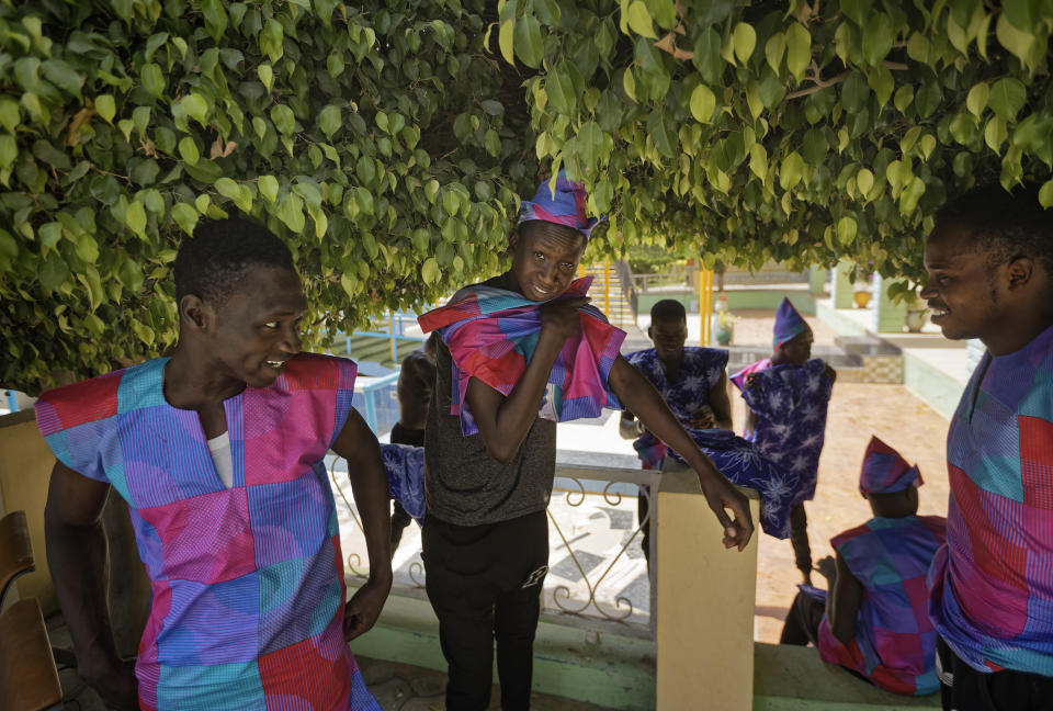 In this photo taken Monday, Feb. 18, 2019, dancers change outfits between scenes under the shade of a tree, as they record a music video calling for a peaceful election, at a golf resort outside of Kano, northern Nigeria. Faced with an election that could spiral into violence, some in the popular Hausa-language film industry known as Kannywood assembled this week to shoot an urgent music video appealing to the country for peace. (AP Photo/Ben Curtis)