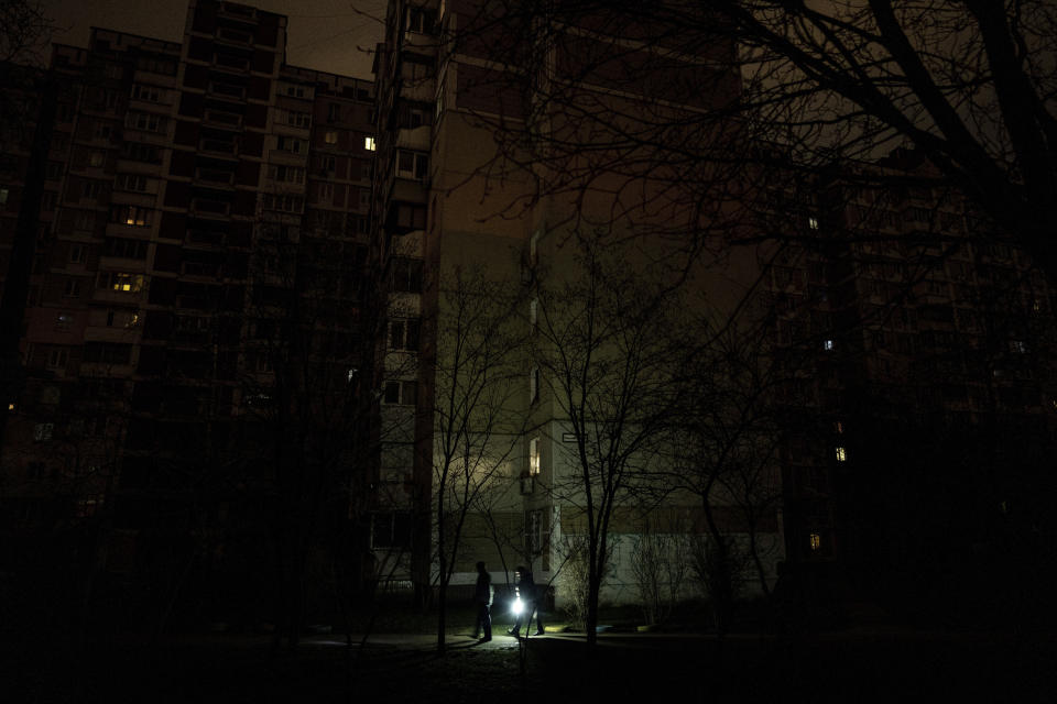 People light up the road with a flashlight during blackout in Kyiv, Ukraine, Friday, Feb. 3, 2023. (AP Photo/Evgeniy Maloletka)