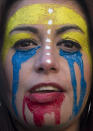 Una mujer con el rostro pintado con los colores de la bandera de Venezuela participa en una manifestación de venezolanos que protestan contra el gobierno del presidente Nicolás Maduro en Madrid, España, el martes 18 de febrero de 2014