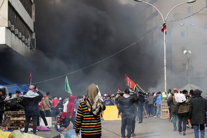 Demonstratos are seen amongst smoke rising from burning tents as Iraqi security forces raid at Tahrir Square during ongoing anti-government protests in Baghdad