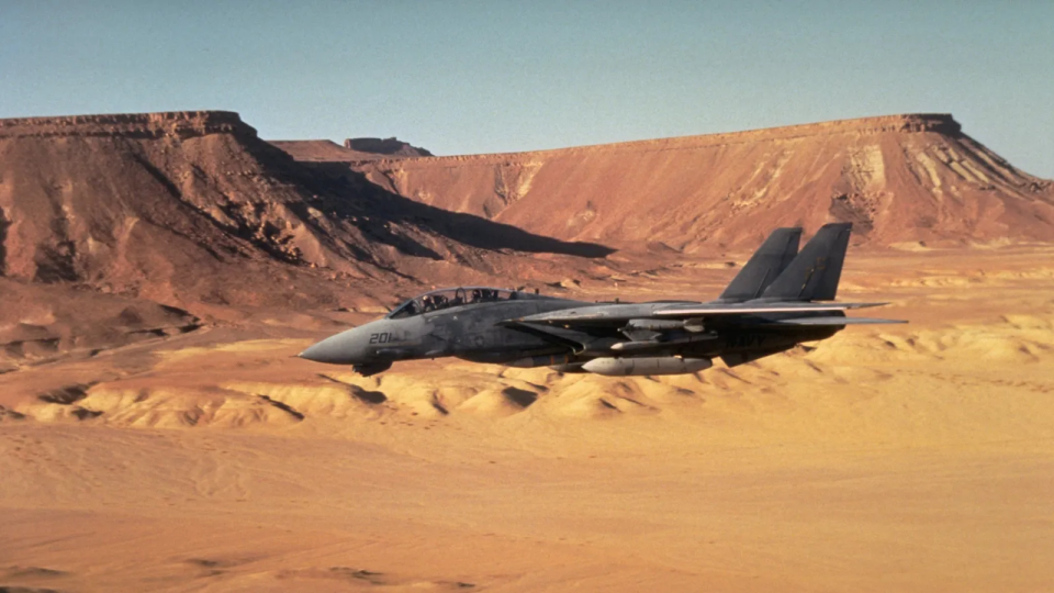 Avión de combate volando sobre un desierto.