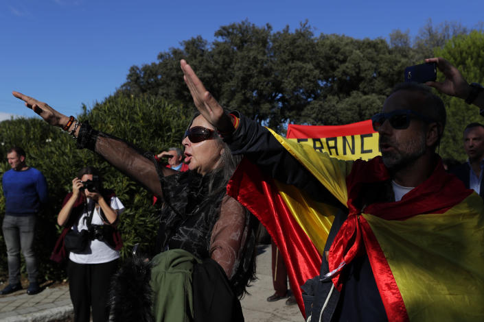 People make the fascist salute as they gather outside Mingorrubio's cemetery, outskirts of Madrid, Thursday, Oct. 24, 2019. Forty-four years after his demise, the remains of Spanish dictator Gen. Francisco are to be dug out of his grandiose resting place outside Madrid and taken to a small family crypt, finally satisfying a long-standing demand of his victims' relatives and others who suffered under his regime. Inscription at ribbons reads in Spanish "Barcelona always with Franco". (AP Photo/Manu Fernandez)
