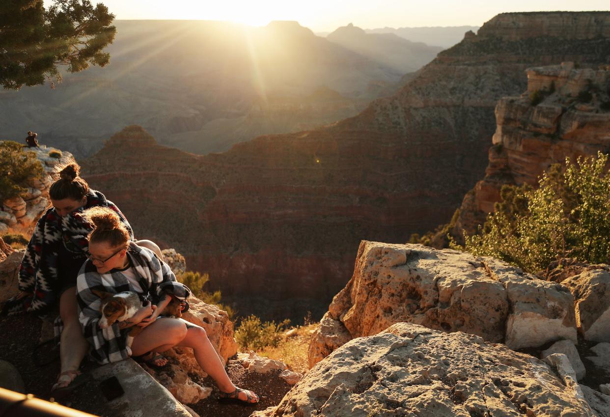 Visitors sit on rocks after sunrise on Memorial Day along the South Rim of Grand Canyon National Park, which has partially reopened on weekends amid the coronavirus (COVID-19) pandemic, on May 25, 2020 in Grand Canyon National Park, Arizona. The park has opened for limited hours and access the past two weekends despite concerns that the mingling of visitors could contribute to the spread of the COVID-19 virus.