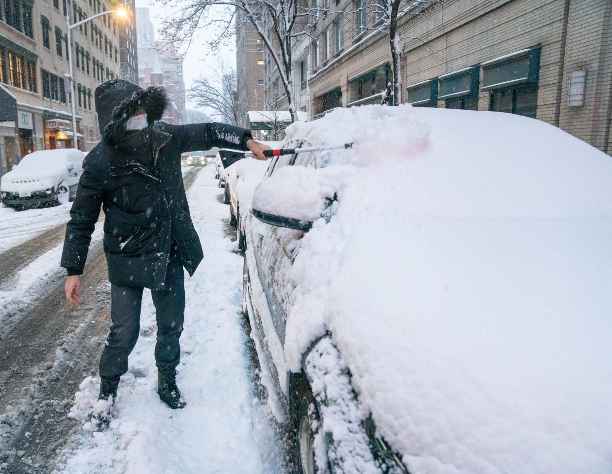 Dimitri Mitanov clears snow from his car on the Upper East Side of Manhattan on Friday, Jan. 7, 2022.