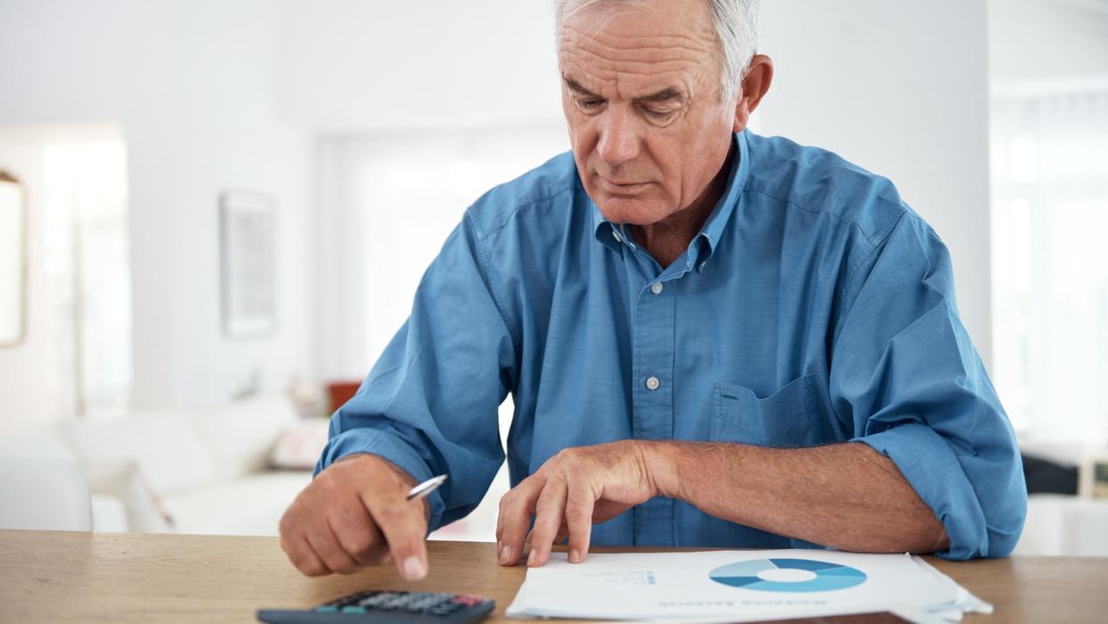 Senior man using a calculator while reviewing his budget