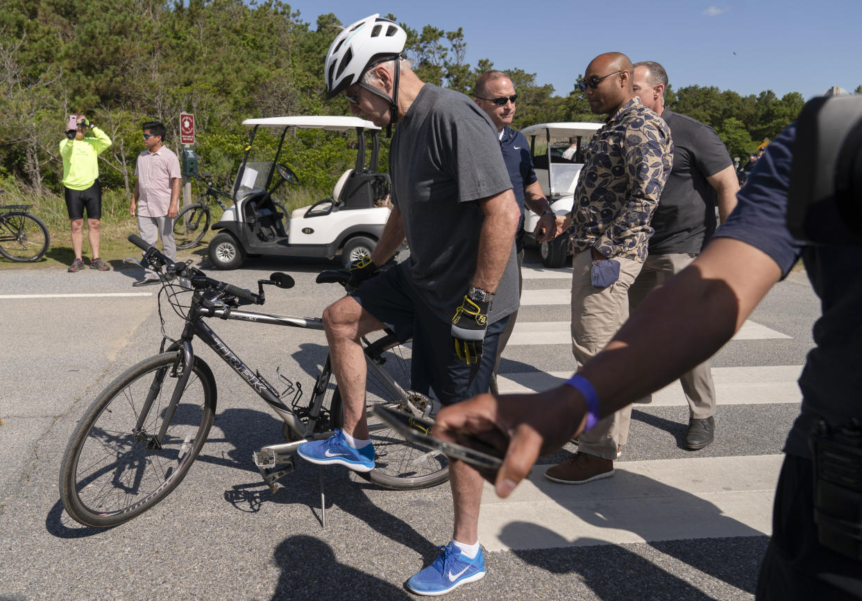 President Joe Biden gets back on his bike after falling when he tried to get off his bike at the end of a ride to greet a crowd at Gordons Pond in Rehoboth Beach, Del., Saturday, June 18, 2022. (AP Photo/Manuel Balce Ceneta)