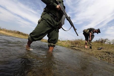 A soldier from the Kachin Independence Army (KIA) puts on his shoes as he and his comrade cross a stream towards the front line in Laiza, Kachin state, January 29, 2013. REUTERS/David Johnson