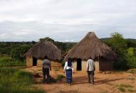 Sylverio Hachiploa (d) camina junto a sus cuidadores Glandwel Muleya (i) y su hermana Abigail Mwaka Mazuba (c) durante la visita en Nedwba.