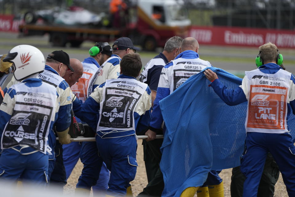 Alfa Romeo driver Guanyu Zhou of China, centre, receives medical treatment after he was involved in a crash at the start of the British Formula One Grand Prix at the Silverstone circuit, in Silverstone, England, Sunday, July 3, 2022. (AP Photo/Frank Augstein)