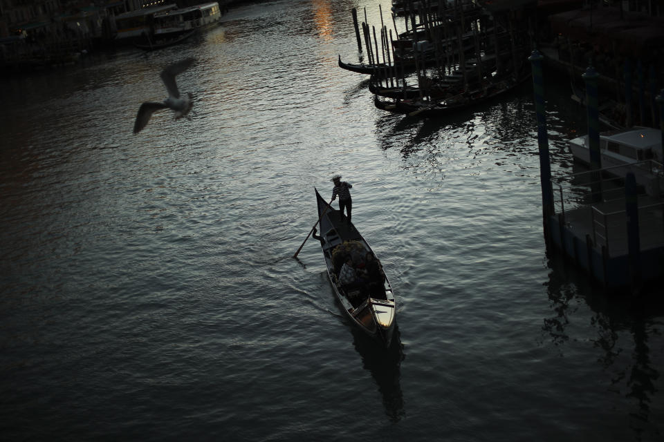 FILE - In this Feb. 28, 2020, file photo, a gondolier travels through the Grand Canal as the sun sets in Venice, Italy. As outbreaks of the new virus that first emerged in China continue to spread in countries, particularly those experiencing winter, one of the biggest unanswered questions is how COVID-19 will behave in warmer weather. (AP Photo/Francisco Seco, File)