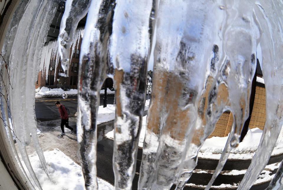 A pedestrian passes near a cluster of slowly melting icicle's on the corner of Mulberry Street and McKenna Court on Tuesday, Feb. 18, 2014, in downtown Scranton, Pa. (AP photo / The Scranton Times-Tribune, Butch Comegys) MANDATORY CREDIT WILKES BARRE TIMES-LEADER OUT;