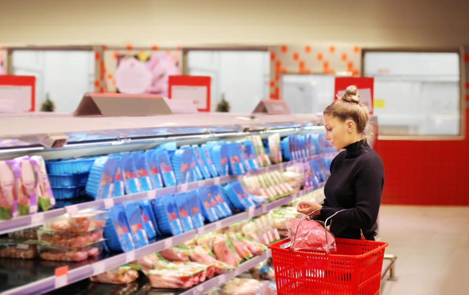 Woman purchasing a packet of meat at the supermarket