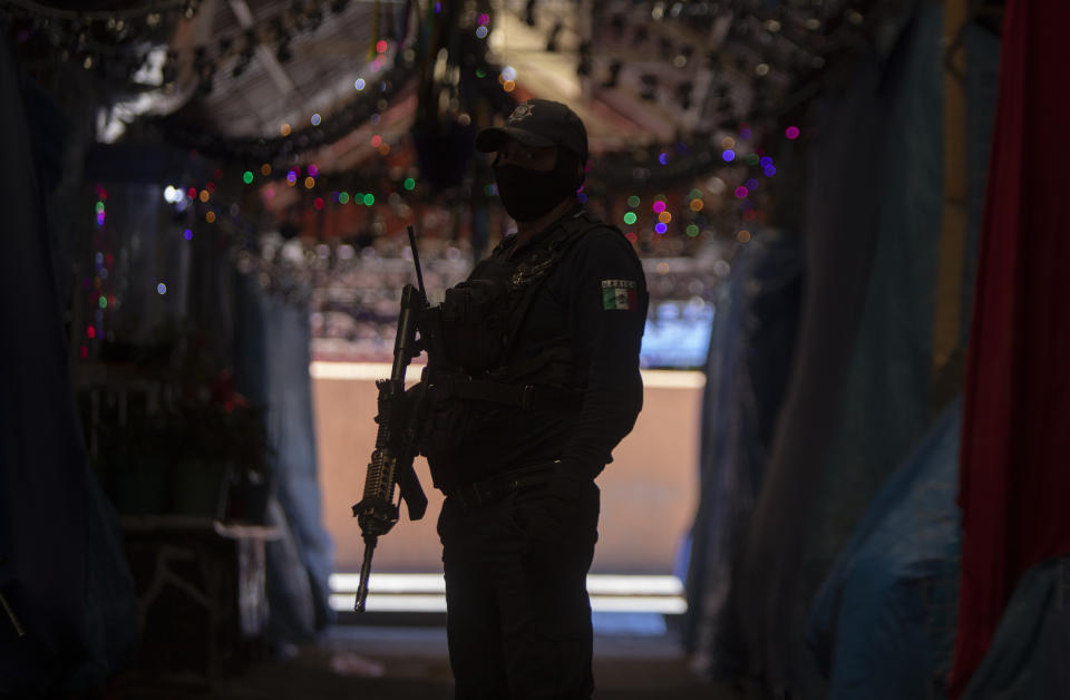 A police officer stand near the area of a massive shootout in Parangaricutiro, Mexico,Thursday, March 10, 2022. Authorities in the avocado-growing zone of western Mexico said five suspected drug cartel gunmen have been killed in a massive firefight between gangs. ( AP Photo/Armando Solis)