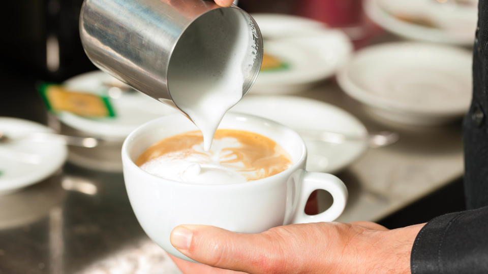 Pouring frothed milk in coffee