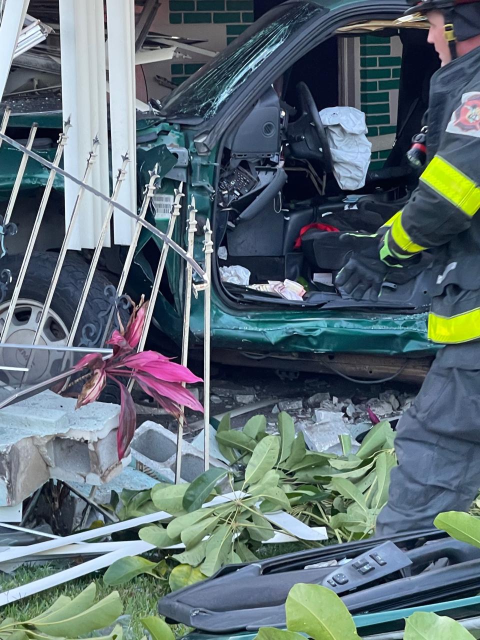 Photographs taken by witnesses show a green pickup truck sitting on the front porch of the home with the driver’s side door completely removed.