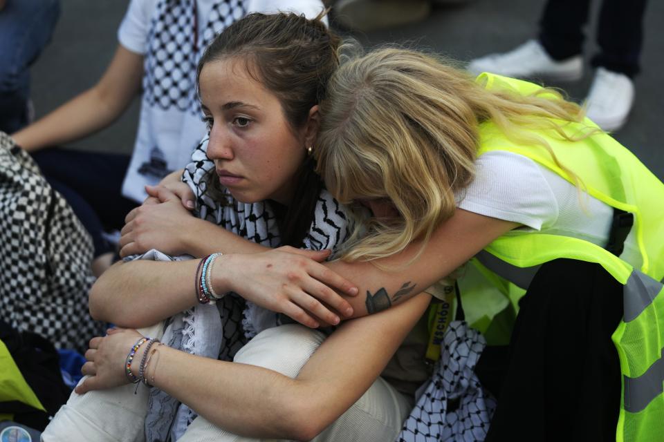 Activists embrace during a demonstrate for climate justice and a ceasefire in the Israel-Hamas war at the COP28 U.N. Climate Summit, Saturday, Dec. 9, 2023, in Dubai, United Arab Emirates. (AP Photo/Rafiq Maqbool)