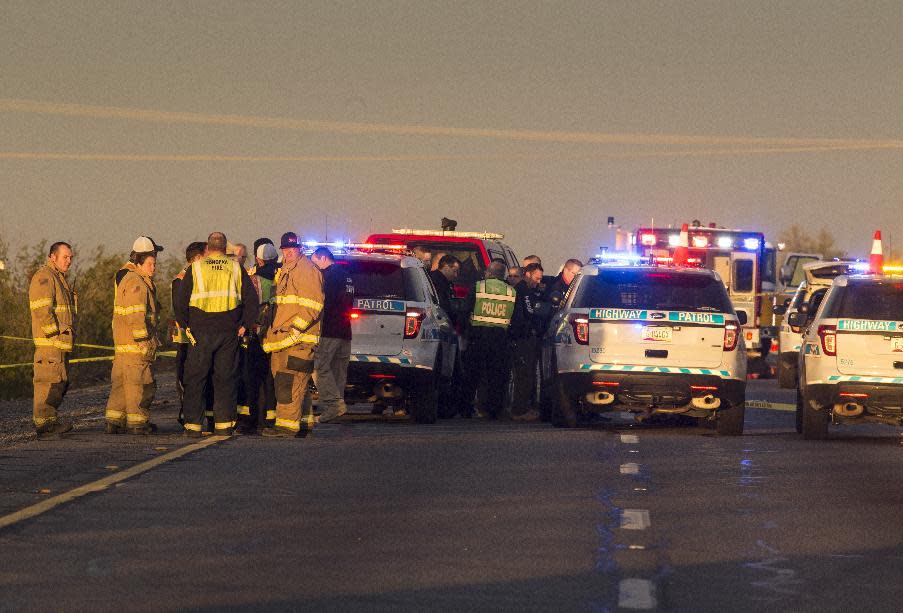 Emergency personnel gather at the scene where an Arizona Department of Public Safety trooper was shot, Thursday, Jan. 12, 2017, at the scene of a rollover accident on Interstate 10 near Tonopah, Ariz. An Arizona state trooper stopped to help at a car wreck along the remote highway Thursday when he was shot and wounded in an ambush by a man who was bashing the officer's head against the pavement until a passing driver shot him to death, authorities said. The trooper suffered a severe wound to his shoulder and upper chest but he is expected to recover at a hospital. (Mark Henle/The Arizona Republic via AP)