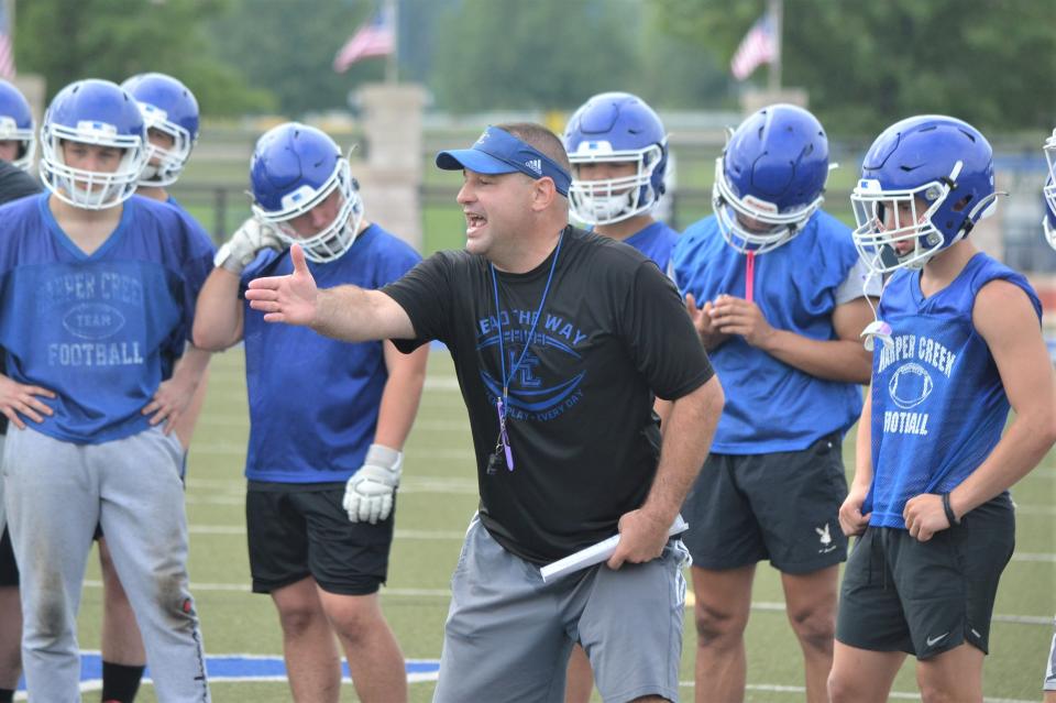 Harper Creek head football coach Mason Converse explains a drill during the first day of preseason practices on Monday.