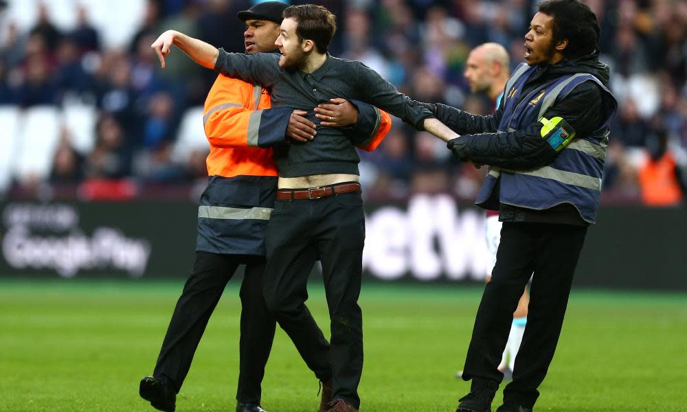 A pitch invader is escorted off the pitch during West Ham’s game with Burnley.