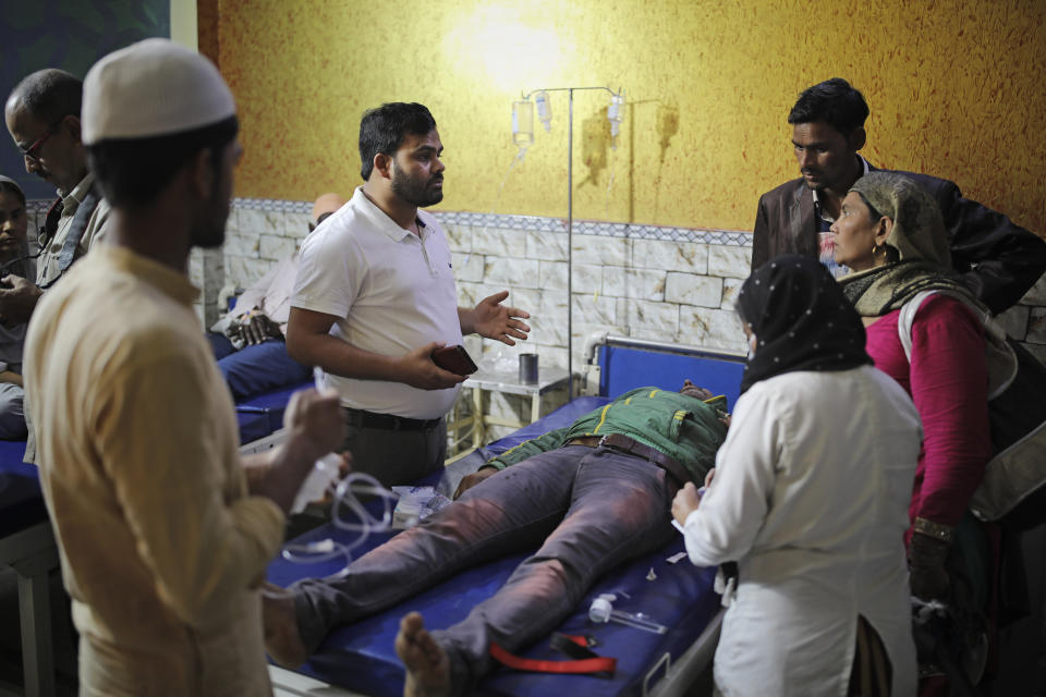 In this Friday, Feb. 28, 2020 photo, Dr. M. A. Anwar, left, speaks to family members of Mehdi Hassan, who was hit by an iron rod by rioters, as he is treated at Al-Hind hospital in Old Mustafabad neighborhood of New Delhi, India. On the eve of U.S. President Donald Trump’s first state visit to India last Sunday, Hindus and Muslims in the Indian capital charged at each other with homemade guns and crude weapons, leaving the streets where the rioting occurred resembling a war zone, with houses, shops, mosques, schools and vehicles up in flames, more than 40 dead and hundreds injured. By mid-afternoon Wednesday, Anwar and his overwhelmed colleagues at the clinic had treated more than 400 people, referring almost 100 to larger hospitals. Dozens, however, remained at the clinic in critical condition. More than 50 people rescued from the riots were given refuge inside Al-Hind hospital, aided by an army of volunteers who provided food and bedding. (AP Photo/Altaf Qadri)