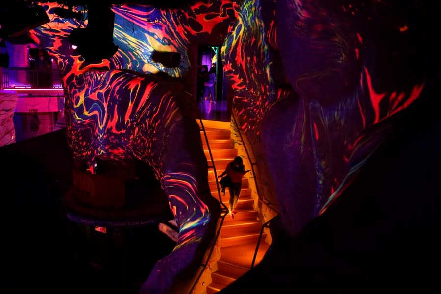A woman walks down stairs while exploring Omega Mart, an immersive art installation by arts production company Meow Wolf, Thursday, Feb. 18, 2021, in Las Vegas. The installation is located at Area15, a retail and entertainment complex in Las Vegas. (AP Photo/John Locher)