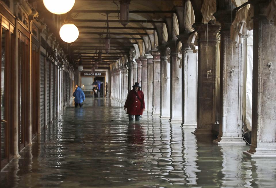 People wade through water on the occasion of a high tide, in a flooded Venice, Italy, Tuesday, Nov. 12, 2019. (Photo: Luca Bruno/AP)