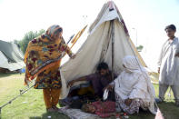 Rubina Bibi, 53, second right, sit near to her family after take refuge at a camp after fleeing her flood-hit homes, in Charsadda, Pakistan, Tuesday, Aug. 30, 2022. Disaster officials say nearly a half million people in Pakistan are crowded into camps after losing their homes in widespread flooding caused by unprecedented monsoon rains in recent weeks. (AP Photo/Mohammad Sajjad)