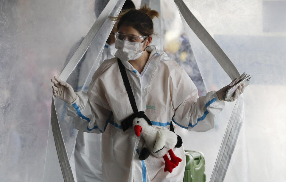 A woman in protective suit passes by a disinfection tent before she enters the departure area of Manila's International Airport, Philippines on Friday, May 22, 2020. Some airlines began flights in and out of the country as the capital eases it's lockdown while it continues to fight the spread of the new coronavirus. (AP Photo/Aaron Favila)