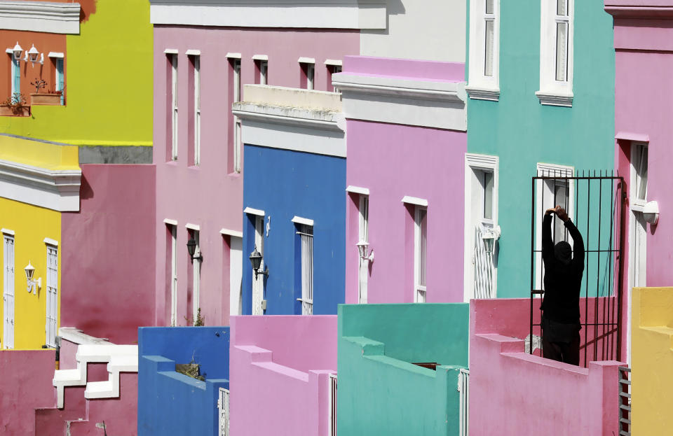 A man stretches, at the entrance of his home in Bo-Kaap, Cape Town, South Africa, Tuesday, April 7, 2020 as South Africa continued its 21 days lockdown in an effort to control the spread of the coronavirus. The virus causes mild or moderate symptoms for most people, but for some, especially older adults and people with existing health problems, it can cause more severe illness or death. (AP Photo/Nardus Engelbrecht)