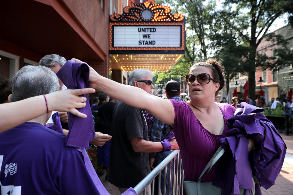 Anna Quillon hands out purple pieces of cloth outside the memorial service.