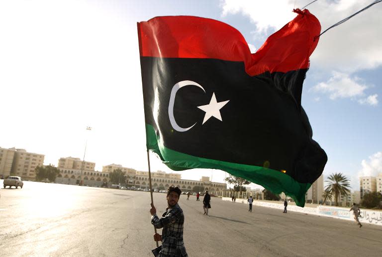 A Libyan man waves his national flag as protesters gather for a demonstration calling on the international community to lift the ban on arming the Libyan army, in the eastern coastal city of Benghazi on February 27, 2015