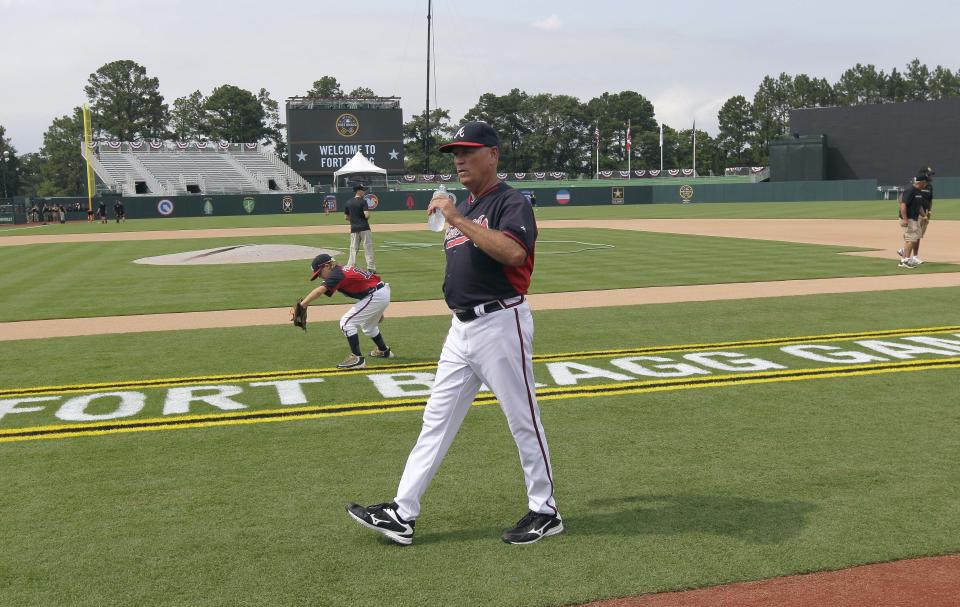 FILE - Atlanta Braves interim manager Brian Snitker walks along the newly built baseball field prior to the team's baseball game against the Miami Marlins in Fort Bragg, N.C., July 3, 2016. The second “Field of Dreams” baseball game is Thursday night, Aug. 11, 2022, in the cornfields of eastern Iowa, near the site of the beloved 1989 movie. If Major League Baseball is looking for another place for a game, oh man, do we have some fun ideas. (AP Photo/Gerry Broome, File)