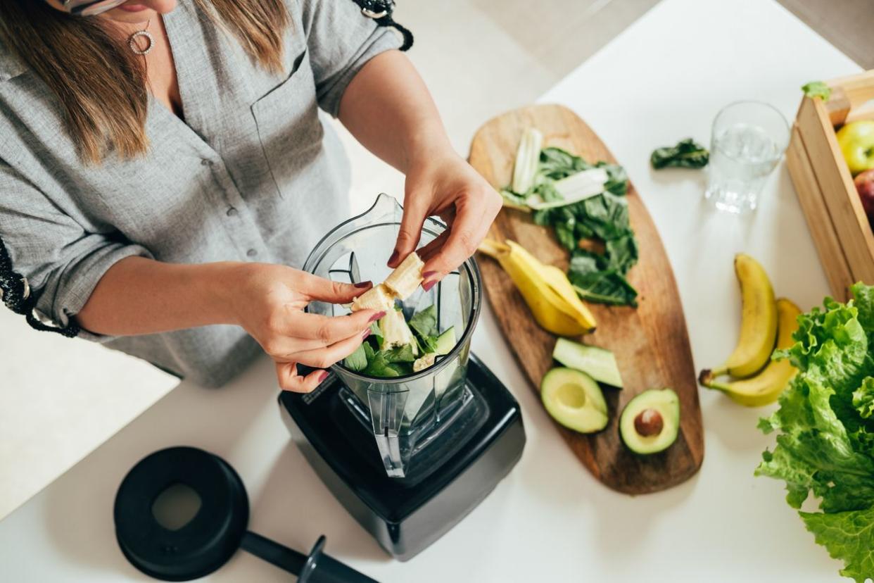 Woman is preparing a healthy detox drink in a blender