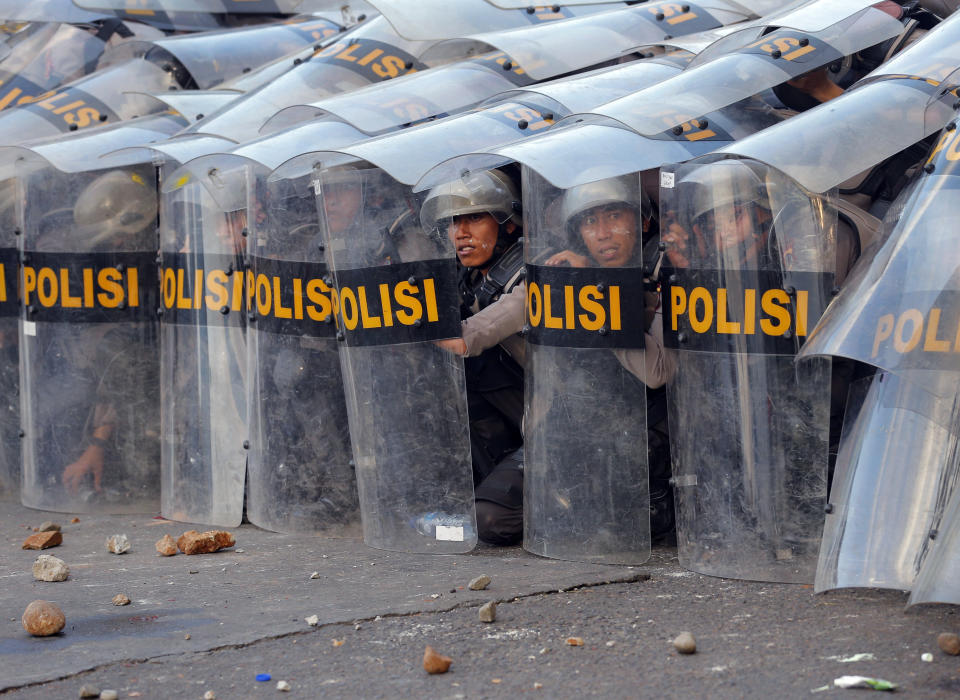 Riot police officers take defensive position during a clash with student protesters in Jakarta, Indonesia, Monday, Sept. 30, 2019. Thousands of Indonesian students resumed protests on Monday against a new law they say has crippled the country's anti-corruption agency, with some clashing with police. (AP Photo/Tatan Syuflana)