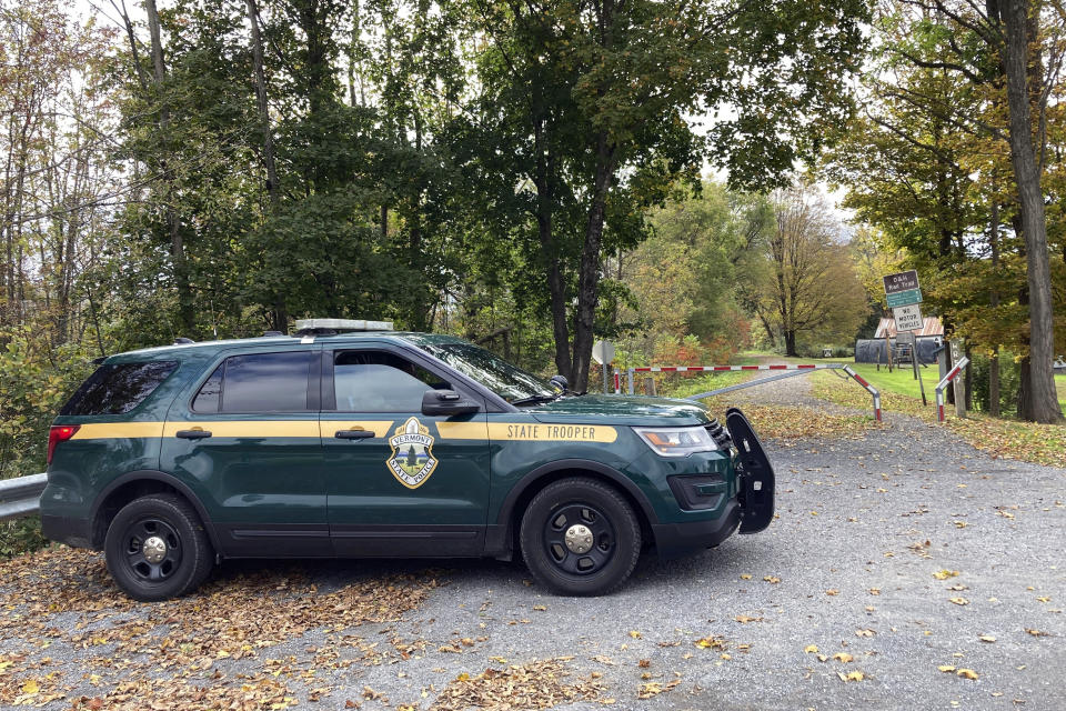 A Vermont State trooper sits parked in a cruiser, Wednesday, Oct. 11, 2023, at the entrance to a recreational trail in Castleton, Vt. Police are searching for the killer of a retired college dean who was shot and killed last week while walking on the trail. (AP Photo/Lisa Rathke)