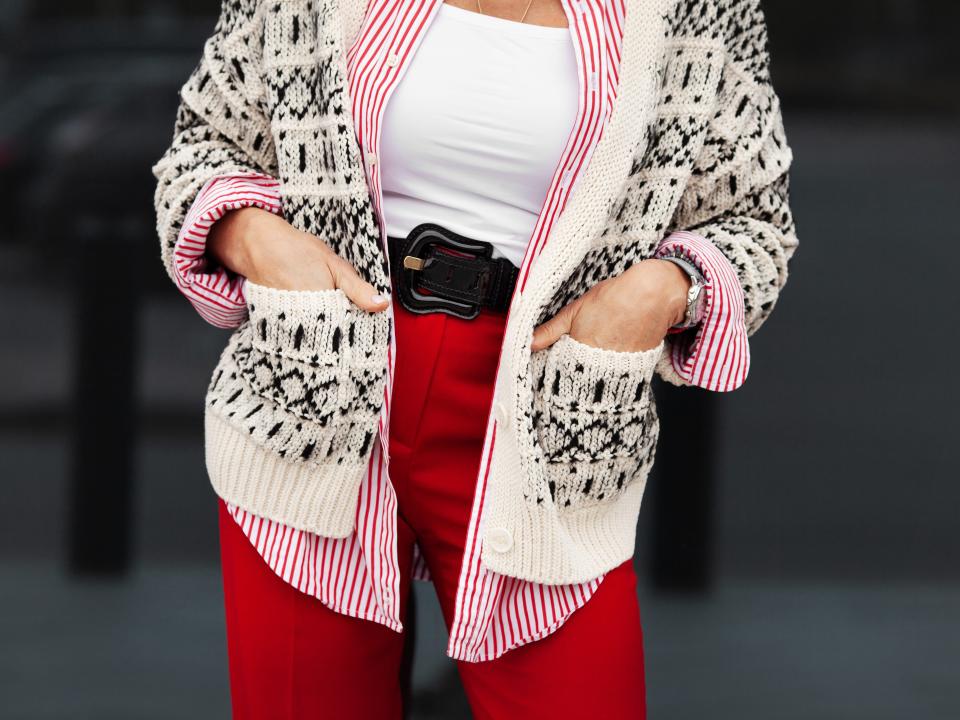 A woman in red pants, a cami, a shirt, and a cardigan
