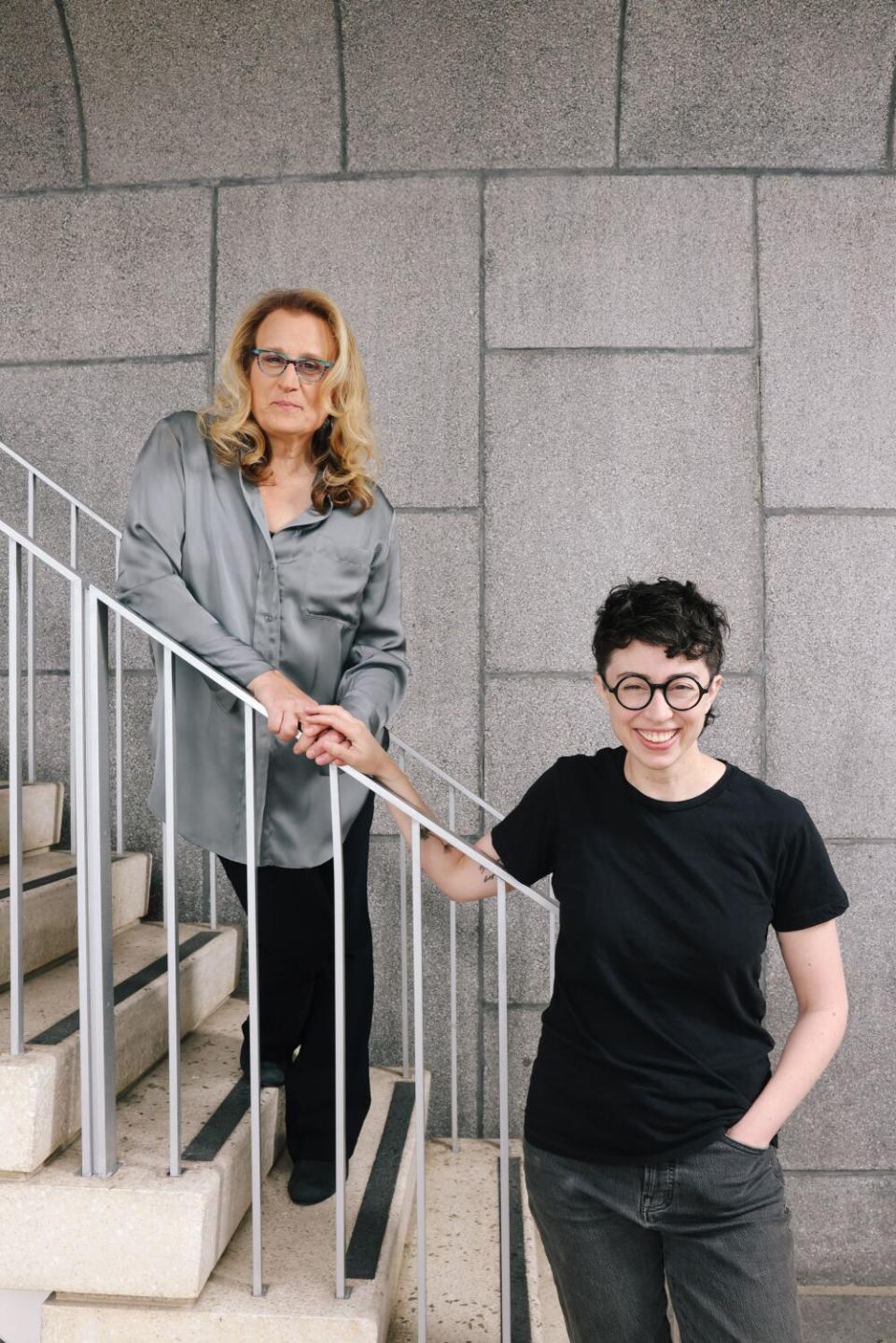 Daya Curley and Adina Verson, standing on stairs and smiling at camera