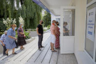 Moldovan citizens wait in line to vote in a snap parliamentary election at a voting station in Chisinau, Moldova, Sunday, July 11, 2021. Moldovan citizens vote in a key snap parliamentary election that could decide whether the former Soviet republic fully embraces pro-Western reform or prolongs a political impasse with strong Russian influence. (AP Photo/Aurel Obreja)