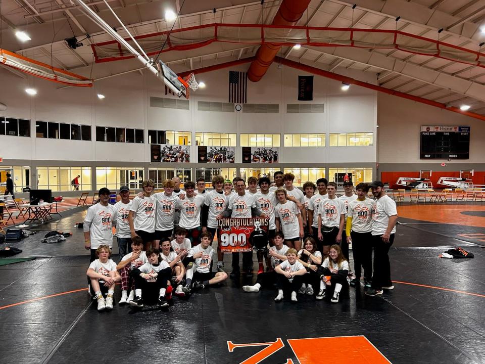 The Hudson wrestling team poses for a photo with head coach Scott Marry after achieving his 900th career dual win.