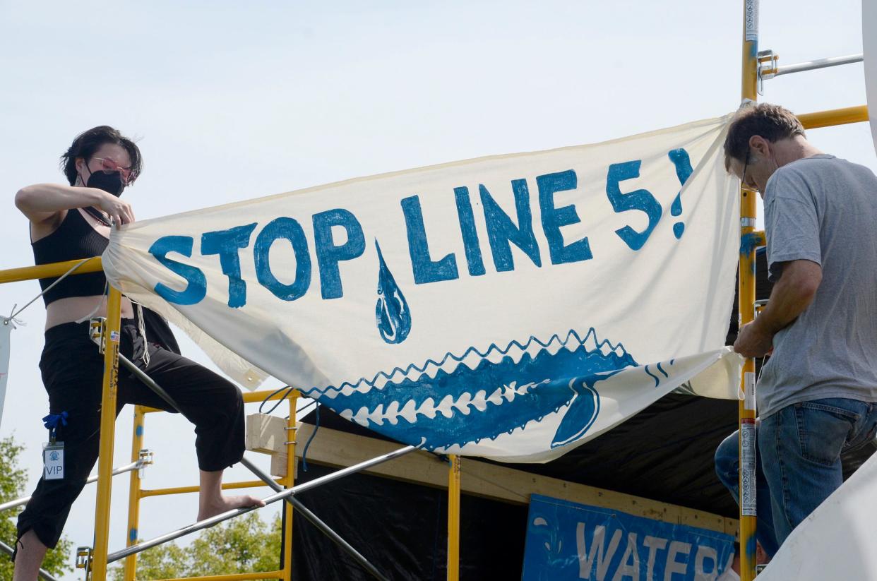 People hang a Stop Line 5 banner on Saturday, Sept. 2, 2023 during the fifth annual Water is Life Festival in Petoskey's Bayfront Park.