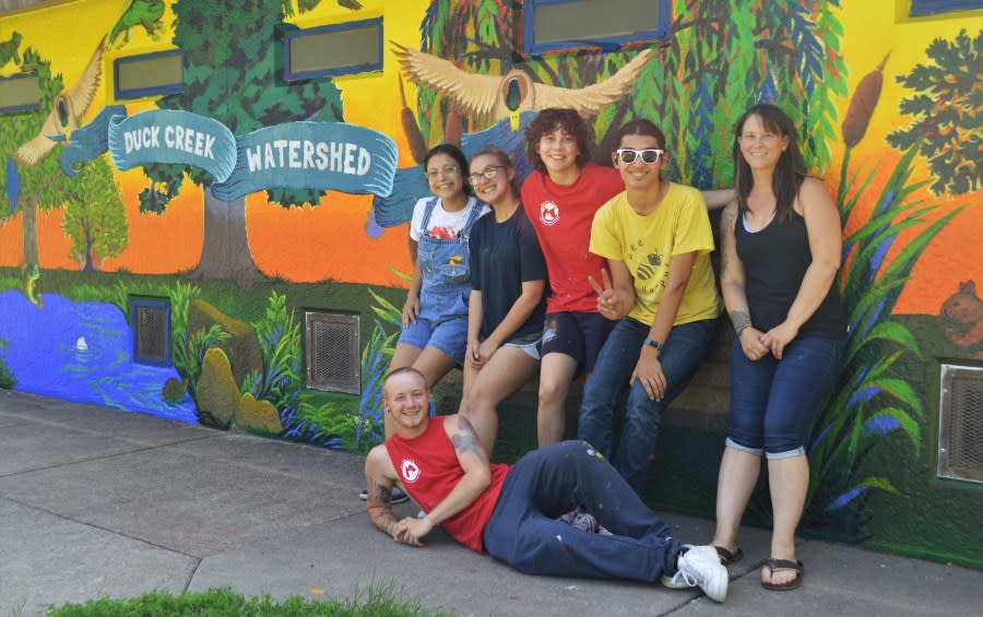 Artist Heidi Sallows (right) with Metro Arts students who painted a watershed mural at Junge Park, Davenport, this past summer. They’re featured in the new “Moved by Waters” film.