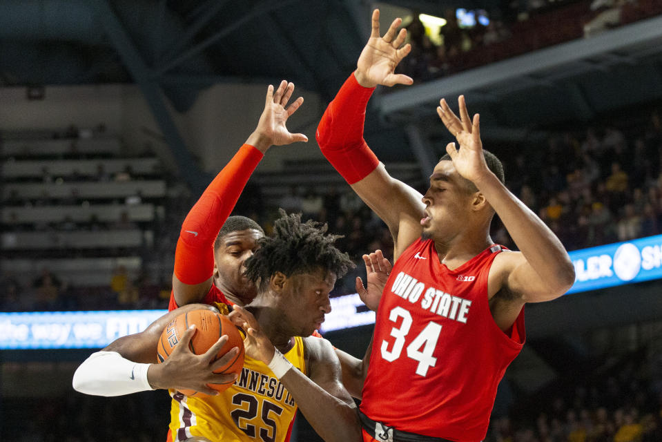 Minnesota center Daniel Oturu (25) looks for an opening against Ohio State center Kaleb Wesson (34) and guard D.J. Carton in the first half of an NCAA college basketball game Sunday, Dec. 15, 2019 in Minneapolis. (AP Photo/Andy Clayton-King)