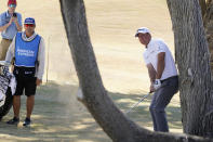 Tom Hoge, right, hits from behind a tree off the fairway rough on the fifth hole during the final round of the American Express golf tournament on the Pete Dye Stadium Course at PGA West, Sunday, Jan. 23, 2022, in La Quinta, Calif. (AP Photo/Marcio Jose Sanchez)