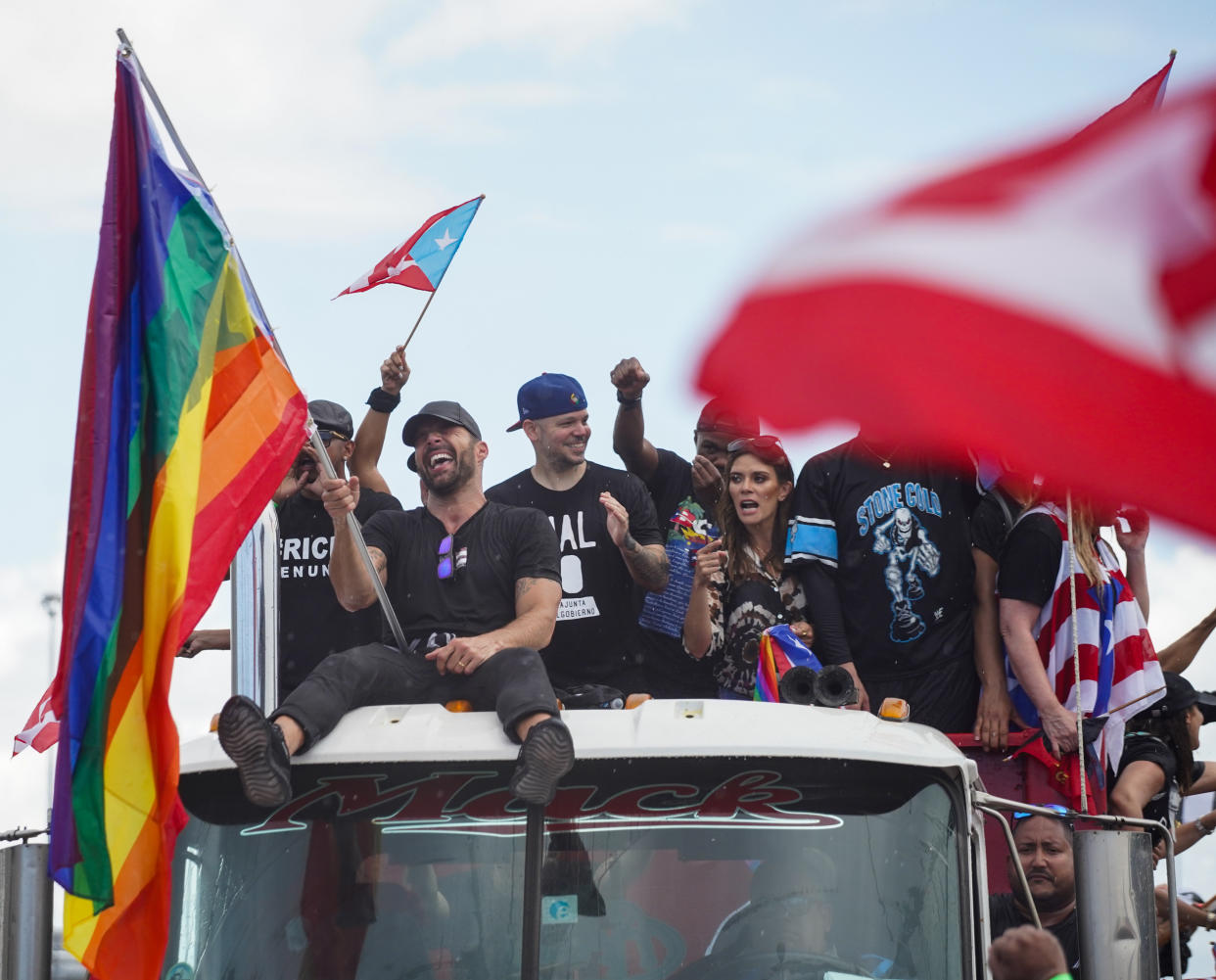 SAN JUAN, PUERTO RICO - JULY 22:  Singer Ricky Martin, sitting left, waves a pride flag as demonstrators walk down  the Las Americas Expressway, the biggest highway in Puerto Rico  as part of a massive march  on July 22, 2019 in San Juan, Puerto Rico. There have been calls for the Governor to step down after it was revealed that he and top aides were part of a private chat group that contained among other messages misogynistic and homophobic messages. (Photo by Angel Valentin/Getty Images)