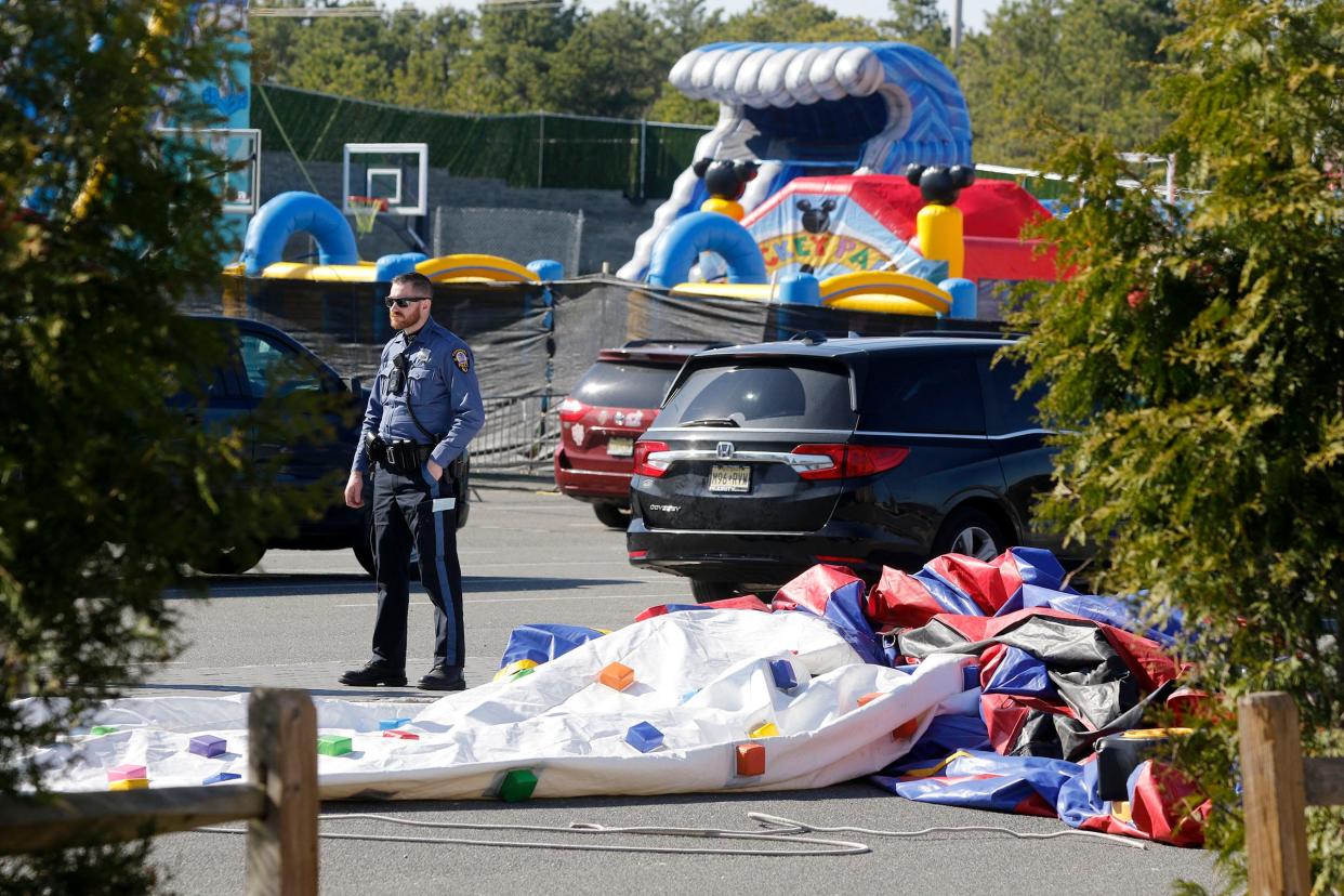 A Lakewood police officer stands by an inflatable amusement ride that broke free - injuring at least three people - during a carnival behind the Ateres Reva Hall in the Township Monday afternoon, April 10, 2023.