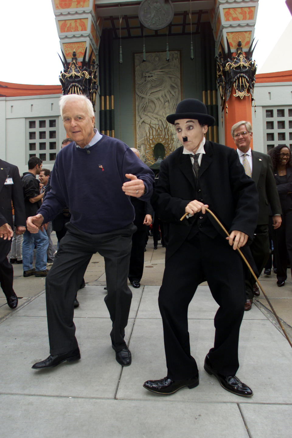 FILE - Candidate for California governor, Richard Riordan, left, imitates the walking style of Charlie Chaplin imitator Audrey Ruttan in front of Mann's Chinese Theater in the Hollywood section of Los Angeles, Monday, Nov. 12, 2001, during a bus tour of the city for Republican activists from around the state highlighting Riordan's record as the city's mayor. Riordan, the moderate Republican multimillionaire who won two terms as mayor in Democrat-friendly Los Angeles and ran unsuccessfully for governor, died Wednesday, April 19, 2023. He was 92.(AP Photo/Damian Dovarganes, File )