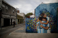 A mural depicting Lionel Messi embraced by teammates decorates a corner wall in the neighborhood of his hometown La Bajada, Argentina, Thursday, Aug. 27, 2020. Fans of Newell's Old Boys hope to lure him home following his announcement that he wants to leave Barcelona F.C. after nearly two decades with the Spanish club. (AP Photo/Natacha Pisarenko)