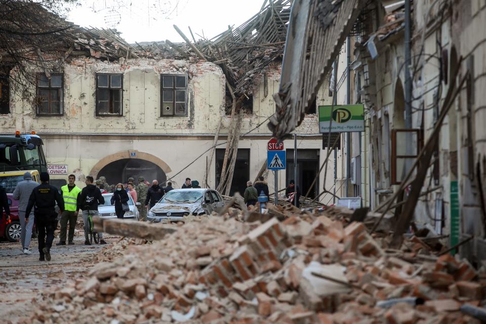 Croatian soldiers, firefighters and residents walk next to damaged buildings in Petrinja, some 50kms from Zagreb, after the town was hit by an earthquake of the magnitude of 6,4 on December 29, 2020. - The tremor, one of the strongest to rock Croatia in recent years, collapsed rooftops in Petrinja, home to some 20,000 people, and left the streets strewn with bricks and other debris. Rescue workers and the army were deployed to search for trapped residents, as a girl was reported dead. (Photo by Damir SENCAR / AFP) (Photo by DAMIR SENCAR/AFP via Getty Images)