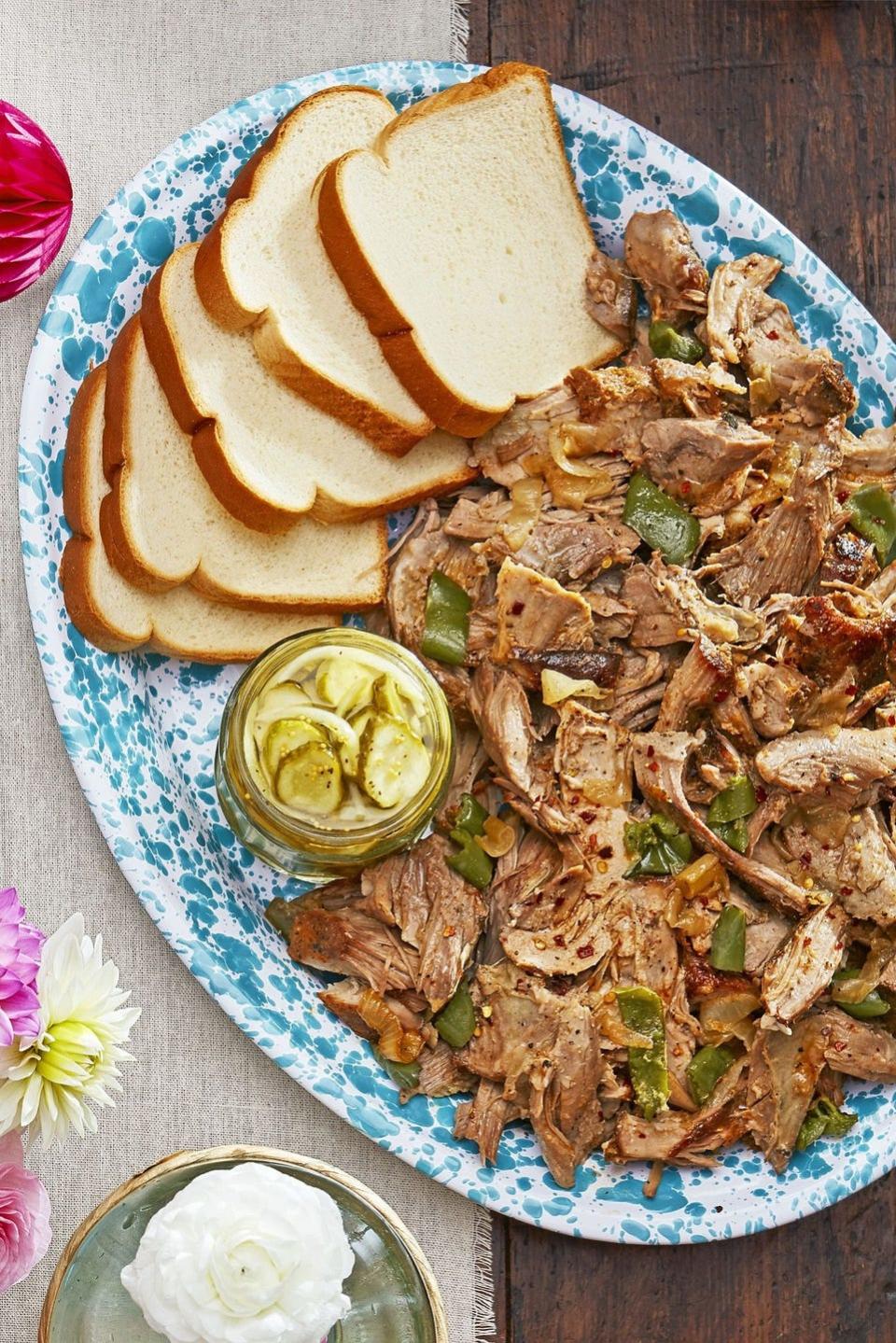 oven roasted pulled pork with sweet and spicy sauce on a serving plate with slices of bread