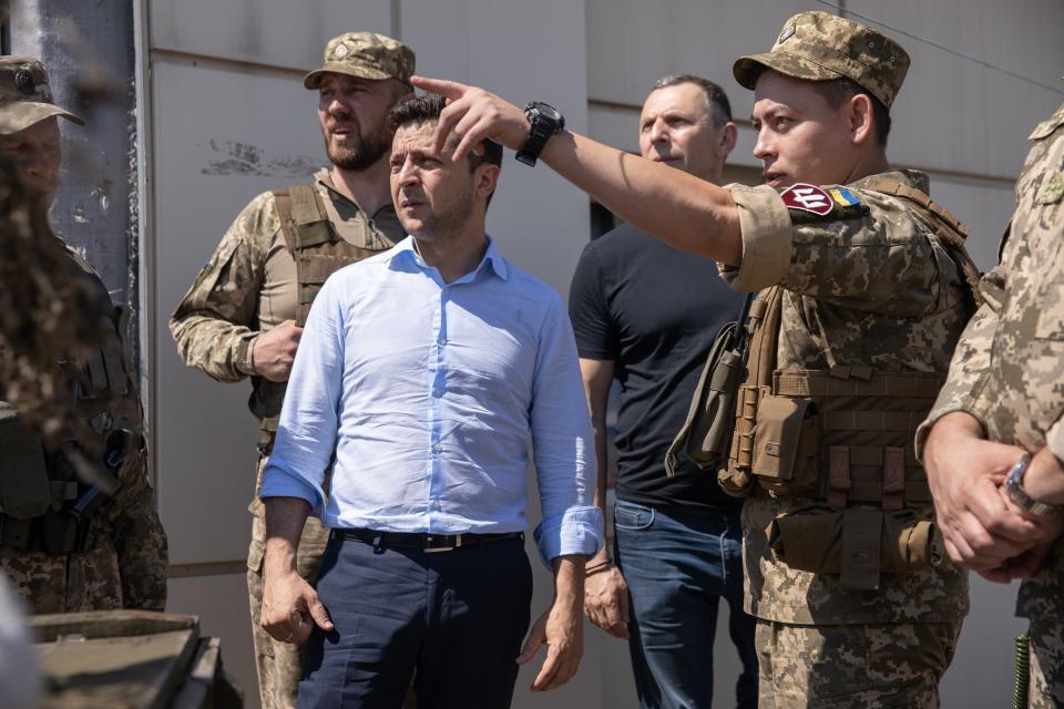 Ukrainian President Volodymyr Zelenskiy, center, listens to a serviceman as he visits the war-hit Luhansk region, eastern Ukraine, Monday, May 27, 2019. (Ukrainian Presidential Press Office via AP)